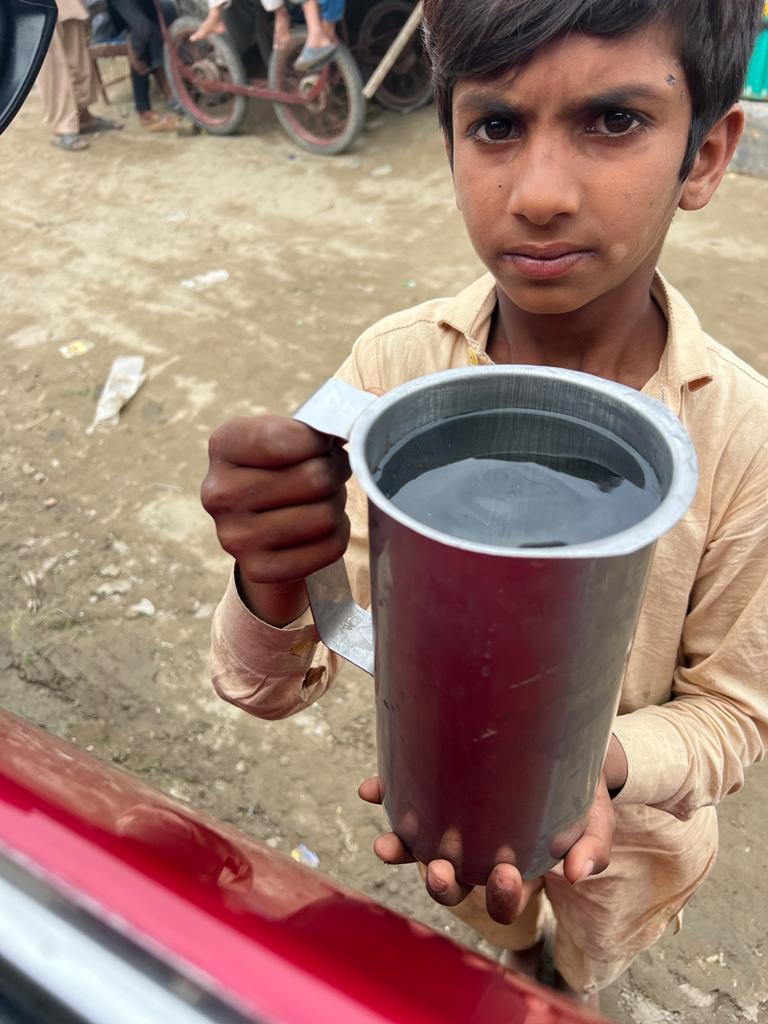 A boy receives energized healing water during a community distribution in Pakistan